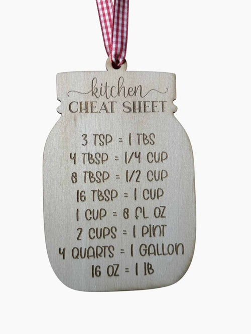 A wooden mason-jar-shaped kitchen cheat sheet ornament with engraved measurement conversions and a red-and-white gingham ribbon hanging from the top.